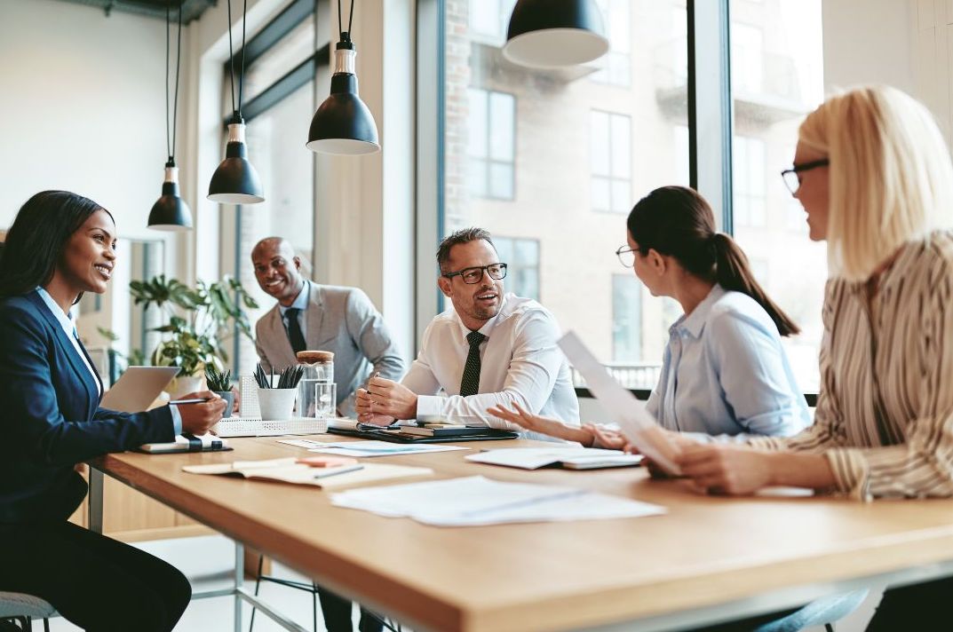 Five professionals sitting around a table talking.