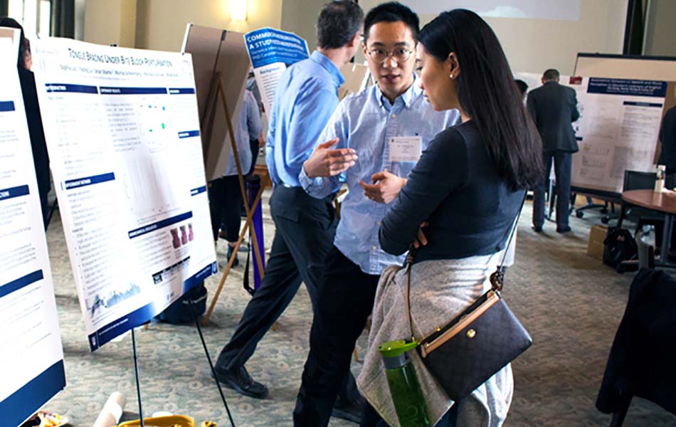 An image of Yadong explaining his poster to Rachel, with Bryan Gick in the background