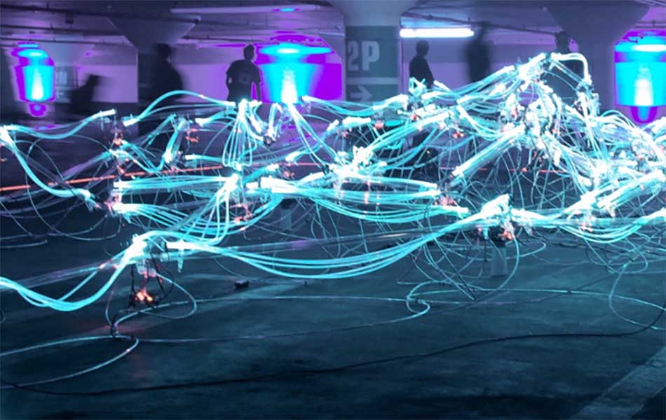 An image of lit up wires criss crossing, with people standing in the background