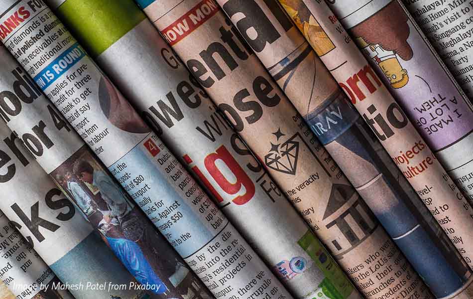 A photo of multiple newspaper spines piled on top of one another
