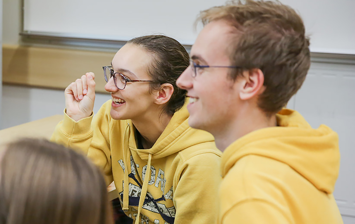 A close up of Paris laughing, and Kelton smiling, both dressed in yellow