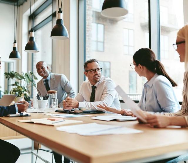 Five professionals sitting around a table talking.