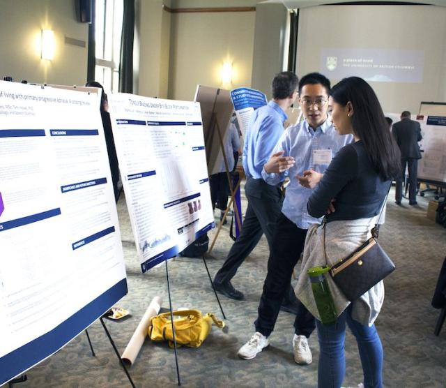 Two students standing in front of research posters in a room, in a discussion