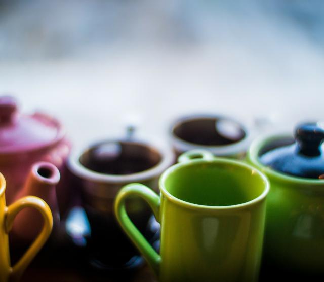 A close up of different coloured mugs and teapots