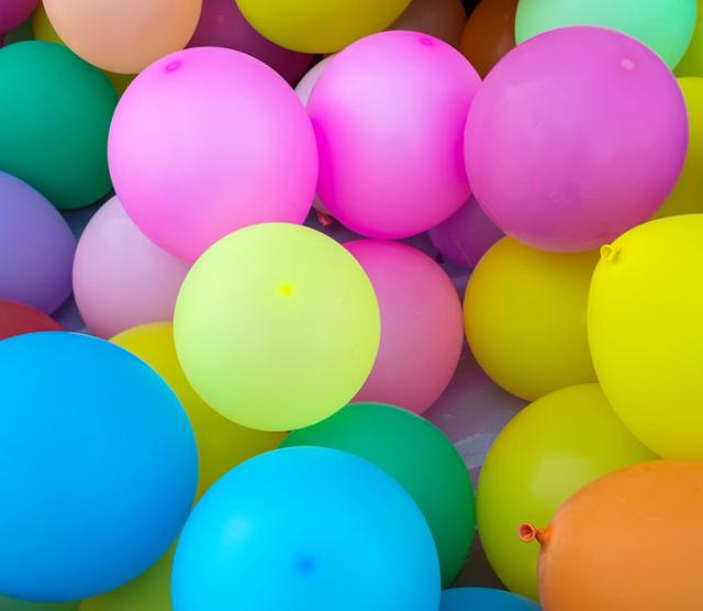 A picture of many different coloured balloons grouped together, including pink, blue, orange, green and yellow balloons.