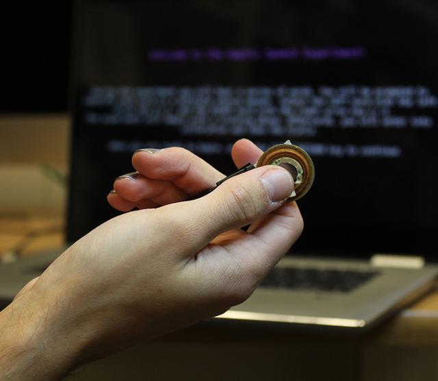 Language Sciences affiliate member David Marino holds the loonie-sized vibrating device used to enhance people's ability to understand speech.