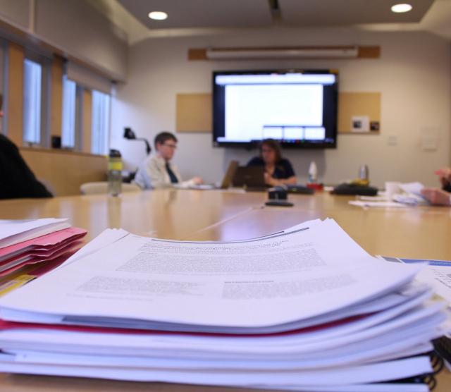 A picture of the HOLa team behind a stack of papers