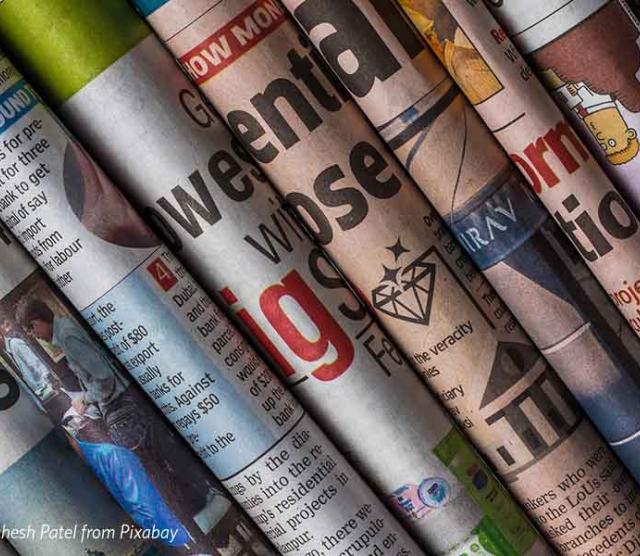 A photo of multiple newspaper spines piled on top of one another