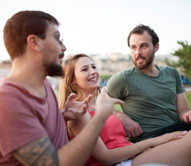 Three people outside having a lively conversation