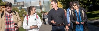 A picture of two students talking to Mark Turin as Janet Werker listens, while the entire group walks up towards the UBC fountain.