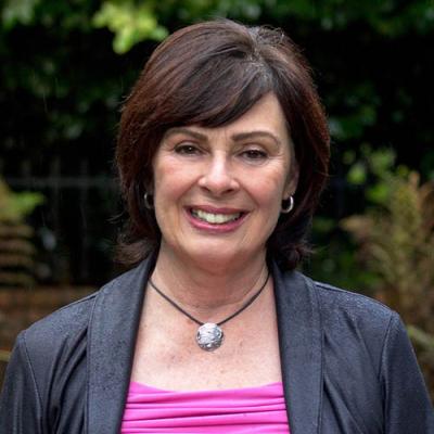 A headshot of Marlene Asselin standing outside, smiling.