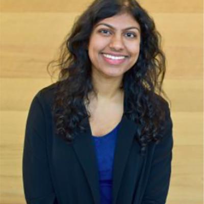 A headshot of Ashley Chand, smiling and wearing a black sweater