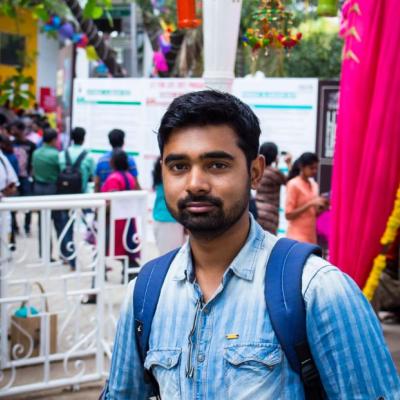 A picture of Debasish Ray Mohapatra wearing a blue shirt and blue backpack, standing on a busy street