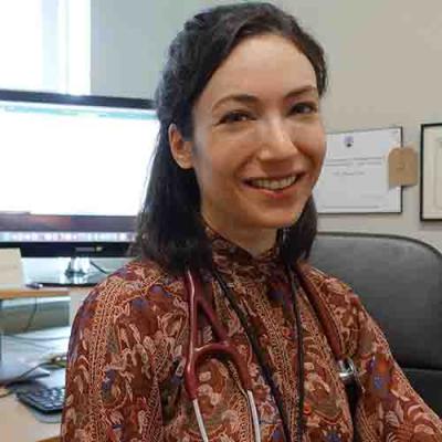 A headshot of Thalia Field sitting at her desk 