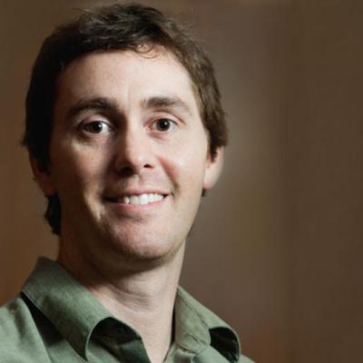 A headshot of Matthew Bedke against a brown background