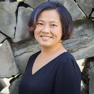 A picture of Qian Wang smiling and standing in front of a rock wall.