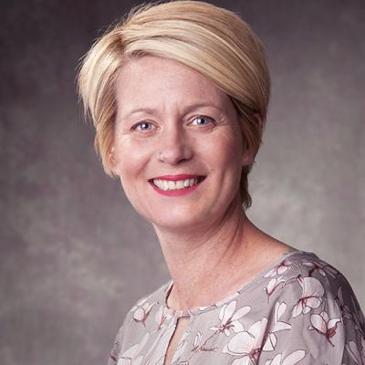 A headshot of Suzanne Curtin in front of a grey background