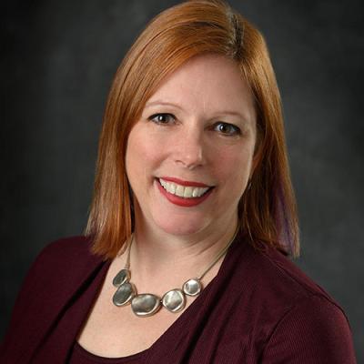 A headshot of Leigh VanHandel against a grey background