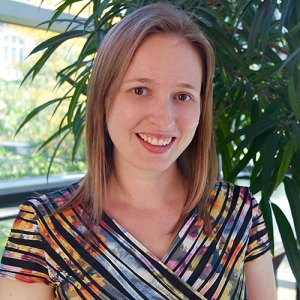 A headshot of Krista Byers-Heinlein standing in front of a plant