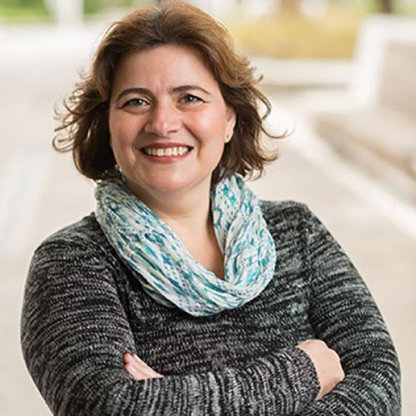 A headshot of Roberta Ballarin standing outside with her arms crossed, smiling