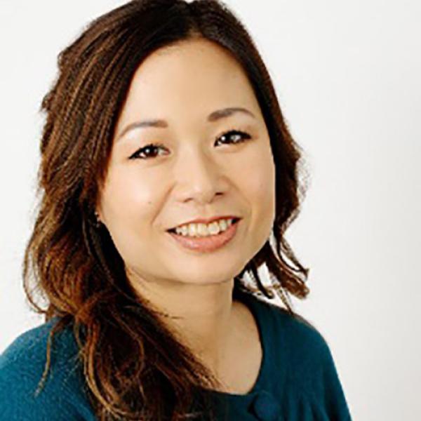 A headshot of Brenda Poon standing in front of a grey background