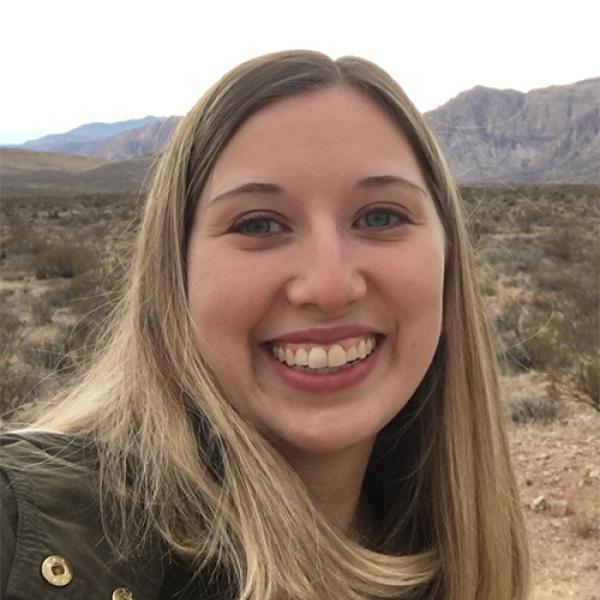 A headshot of Jennifer Campbell smiling, and standing in front of mountains