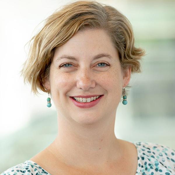 A headshot of Christine Schreyer, smiling and wearing a polka dot shirt