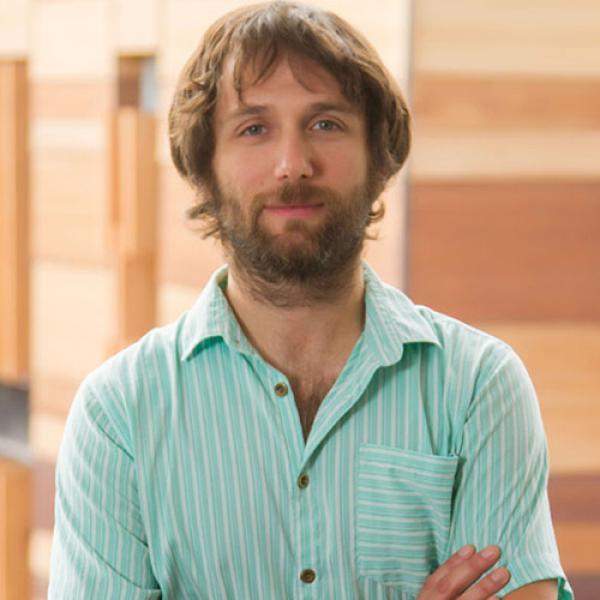 A headshot of Edmundo Kronmüller standing in front of wooden beams