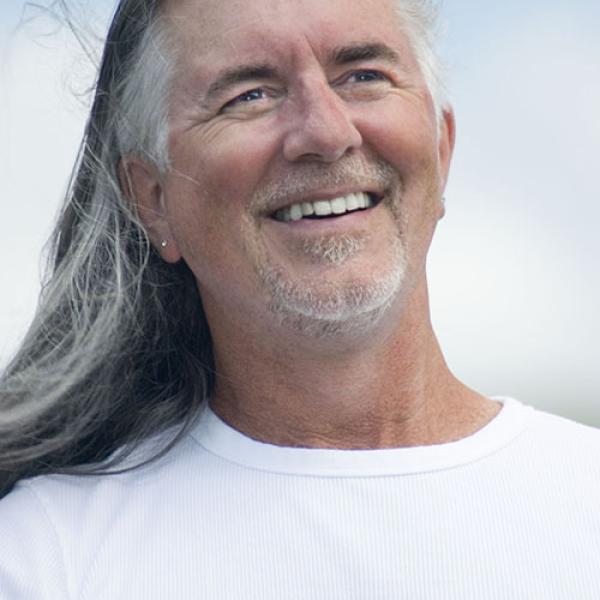 A headshot of Carl Leggo against a blue sky