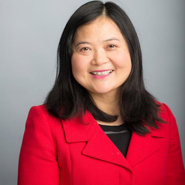 A headshot of Guofang Li standing in front of a grey background