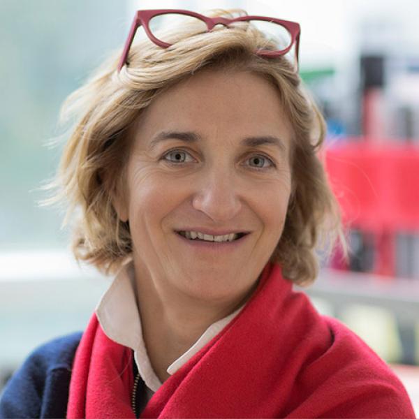 A headshot of Luisa Canuto wearing a scarf and reading glasses on her head