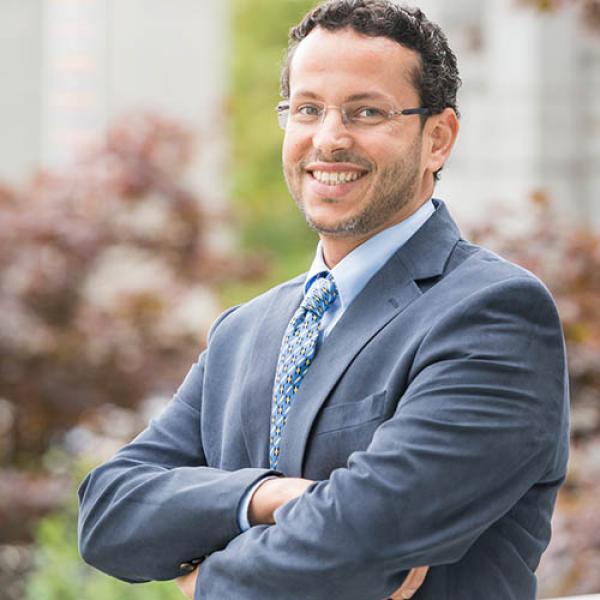 A headshot of Muhammad Abdul-Mageed standing side on to the camera with arms crossed
