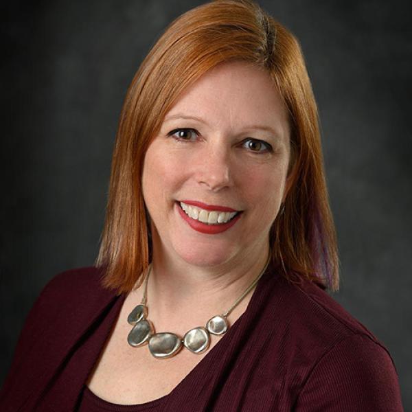 A headshot of Leigh VanHandel against a grey background