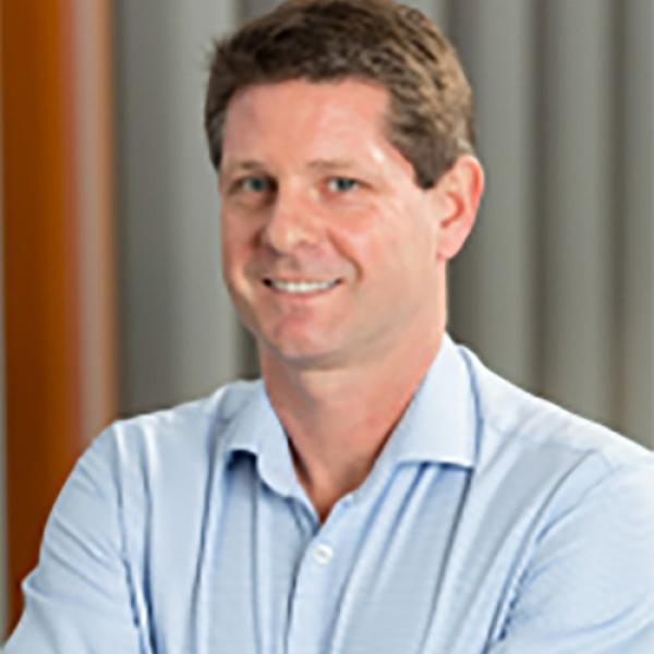 A photo of director of the Cognitive Neuroscience of Schizophrenia (CNoS) Laboratory, Professor Todd Woodward in a blue shirt against a grey background.